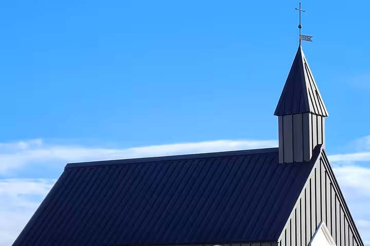 Black church steeple with cross against blue sky on Snaefellsnes Peninsula, Iceland