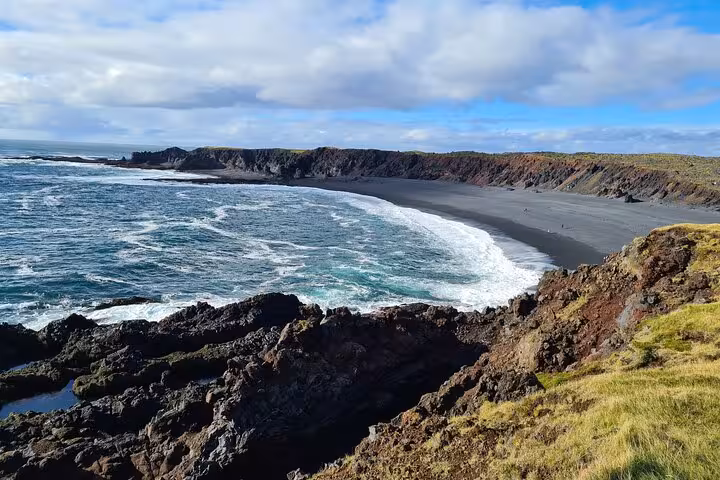 Black sand beach with volcanic rock cliffs and ocean waves on Snaefellsnes Peninsula, Iceland