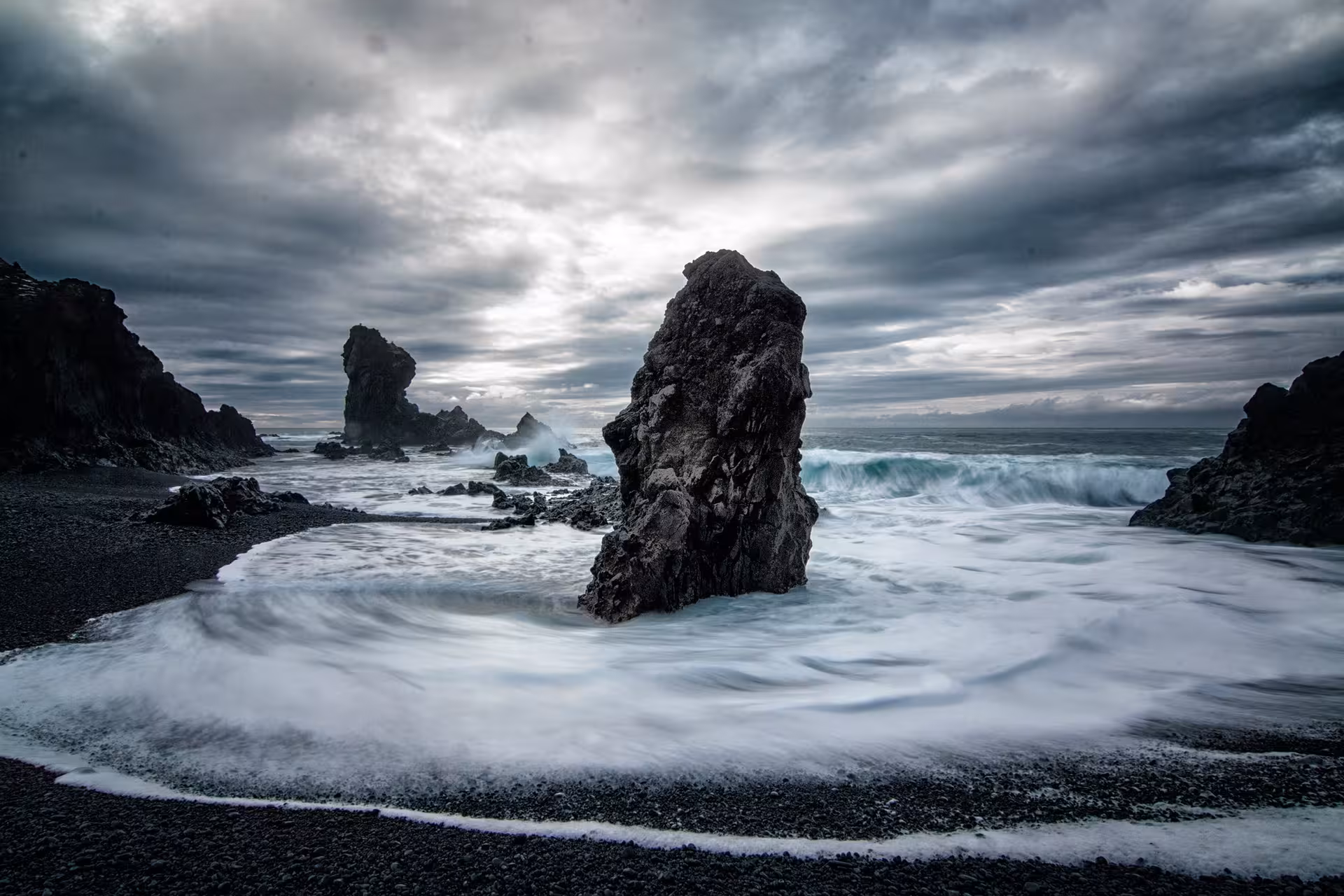 Dramatic black sand beach with towering volcanic sea stacks and crashing waves on Snaefellsnes Peninsula, Iceland