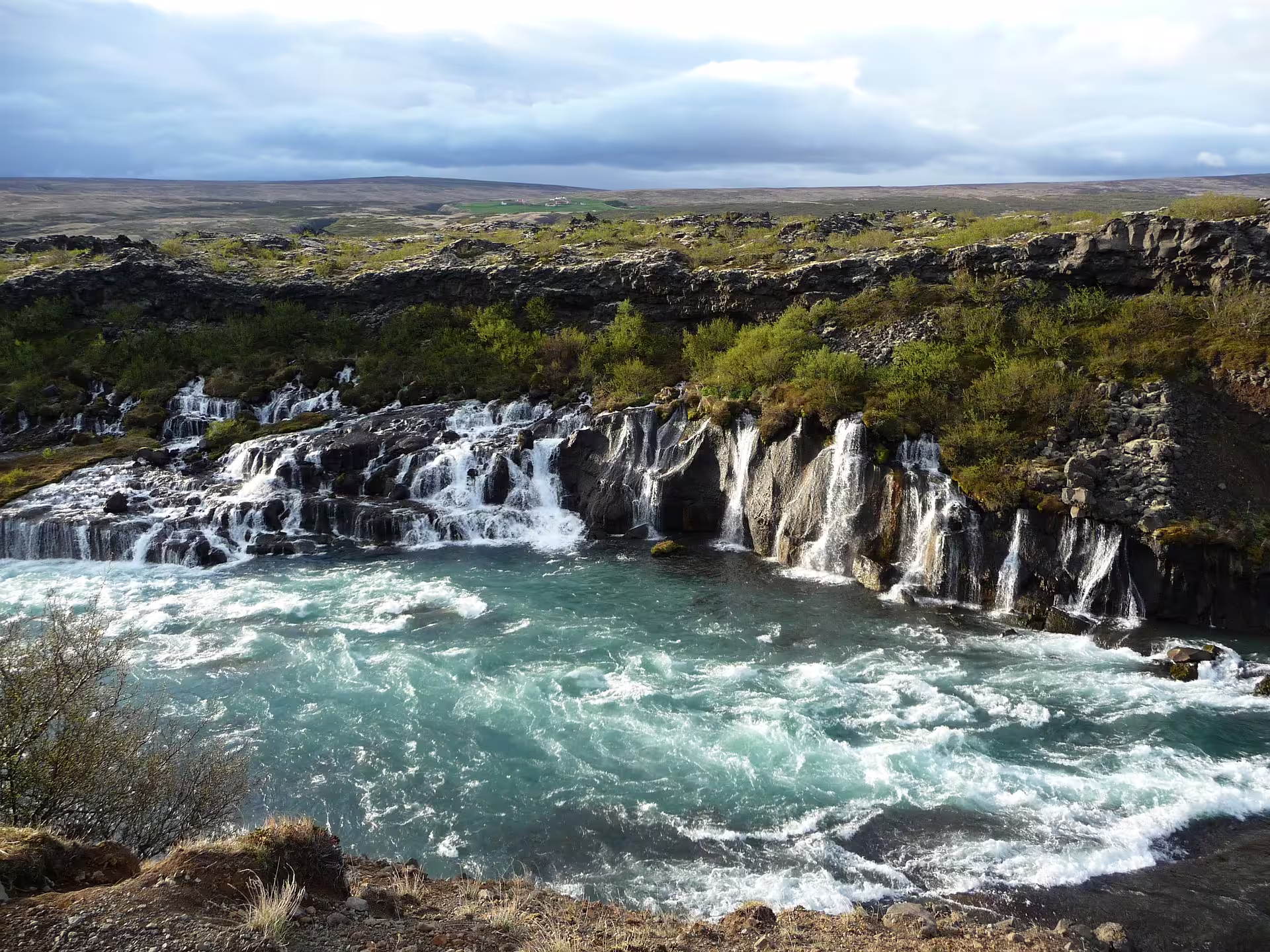 Cascading waterfalls flowing into turquoise glacial river on Snaefellsnes Peninsula, Iceland