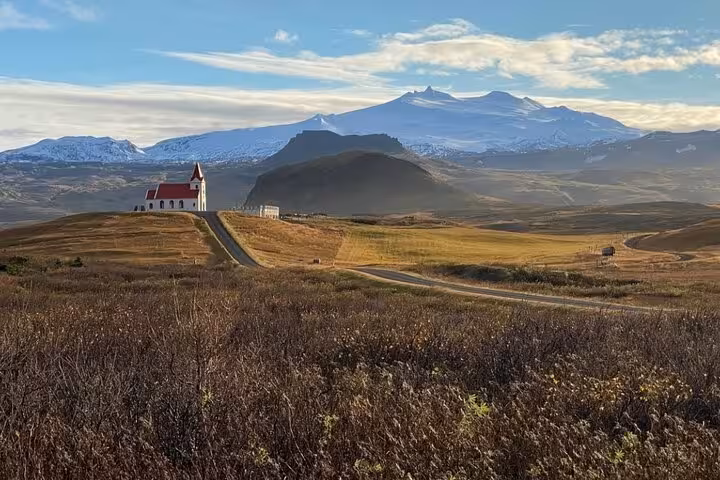 White church with red roof on rolling hills with snow-capped Snæfellsjökull glacier in background, Snaefellsnes Peninsula Iceland