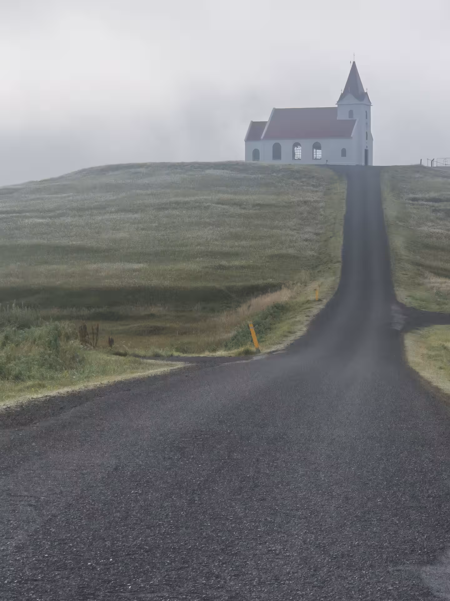 White church on misty hilltop along a narrow road on Snaefellsnes Peninsula, Iceland