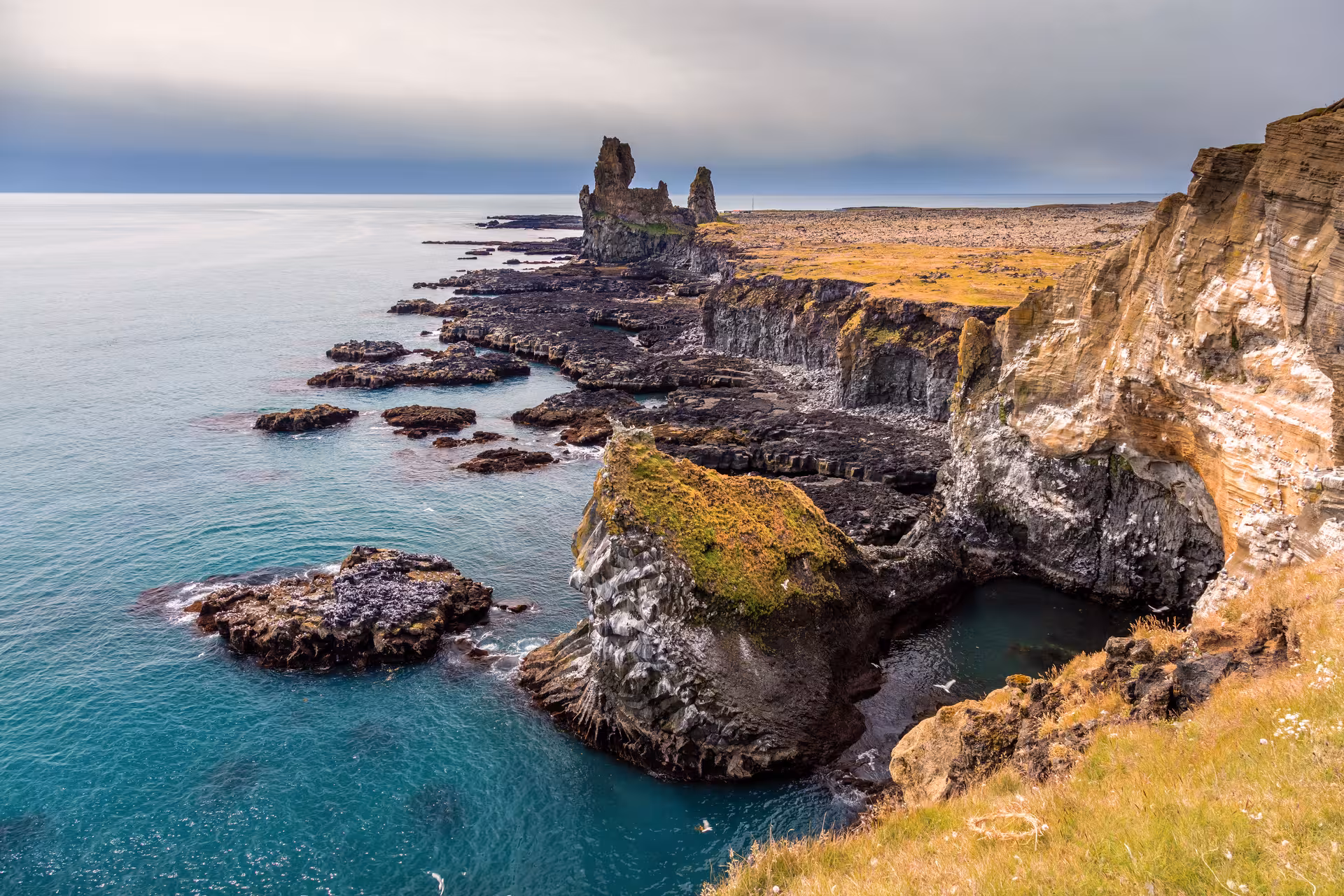 Scenic coastal cliffs of Snæfellsnes Peninsula with rugged rock formations and turquoise sea, ideal for private tours.