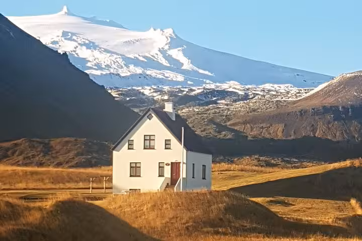 White farmhouse on golden fields with snow-capped Snæfellsjökull glacier and mountain backdrop, Snaefellsnes Peninsula Iceland