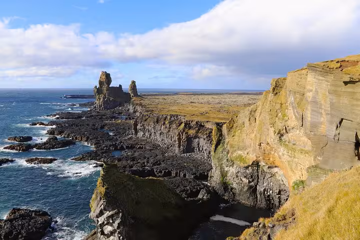 Dramatic black lava rock cliffs and sea stacks along the rugged Snaefellsnes Peninsula coastline in West Iceland
