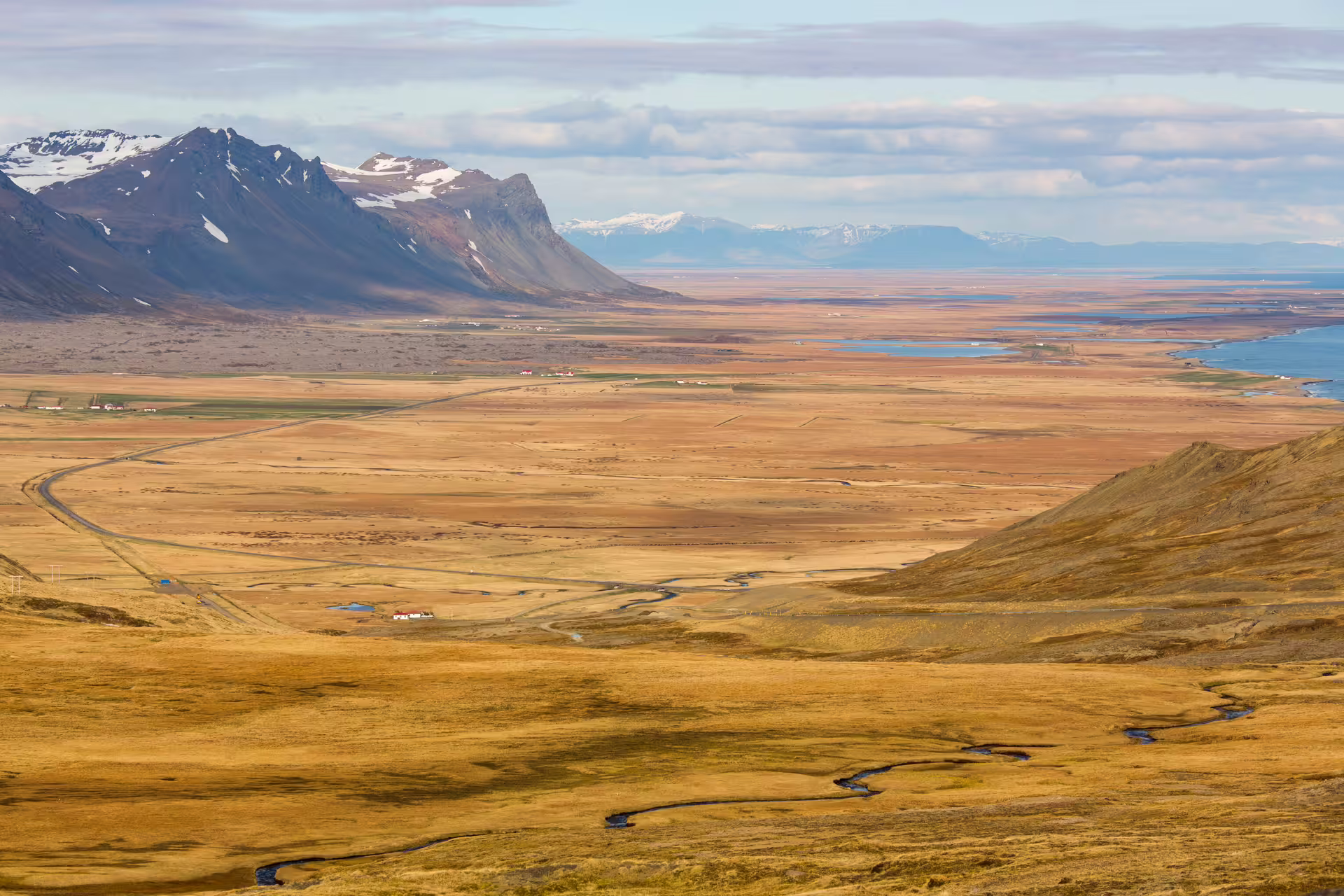 Sweeping aerial view of Snaefellsnes Peninsula golden lava fields with snow-capped mountains and coastal fjords on a private day trip from Reykjavik