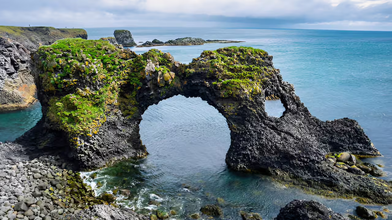 Mossy lava rock arch over turquoise sea on the Snaefellsnes Peninsula, Iceland