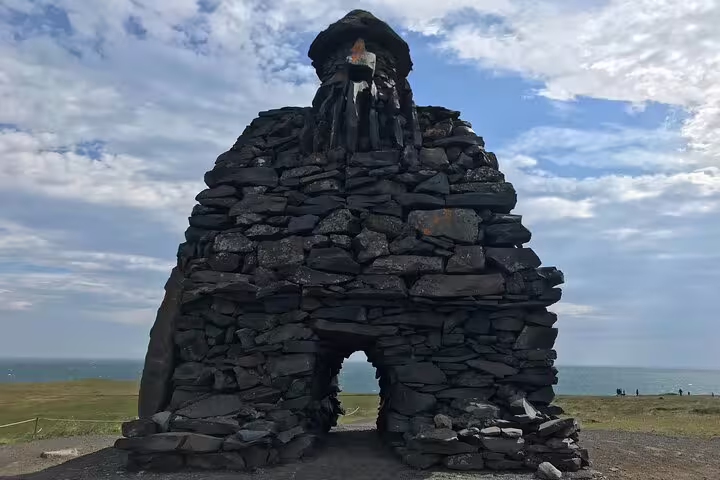 Ancient dark lava rock stone monument on Snaefellsnes Peninsula with ocean backdrop