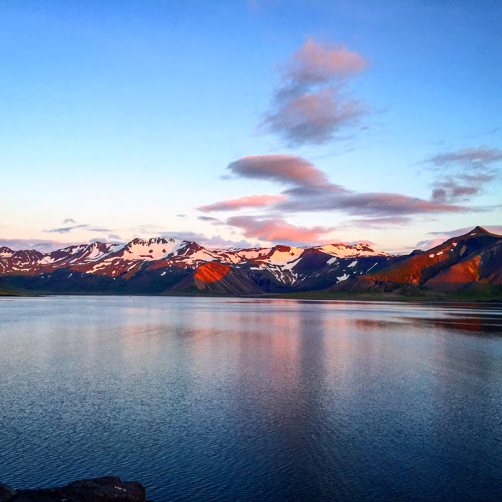 Snow-capped mountains reflecting in a calm lake at sunset on the Snaefellsnes Peninsula, Iceland