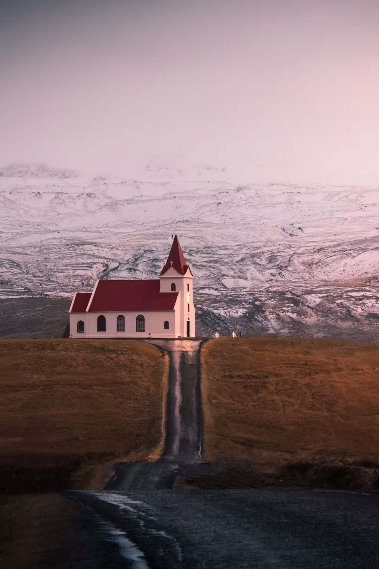 White church with red roof on Snaefellsnes Peninsula, Iceland, with snow-capped mountains behind
