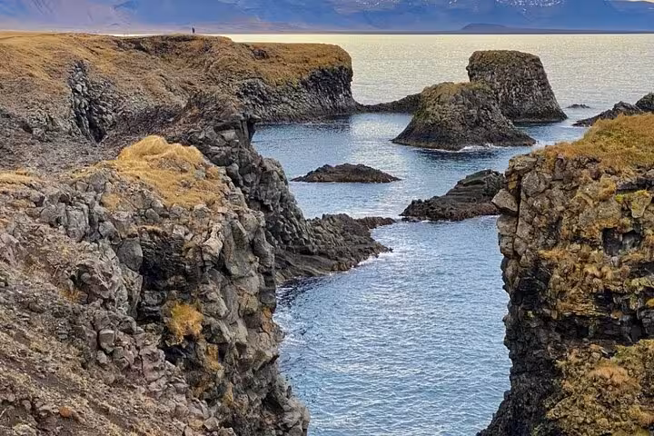 Rocky volcanic coastline with sea stacks and blue waters at Snaefellsnes Peninsula, Iceland
