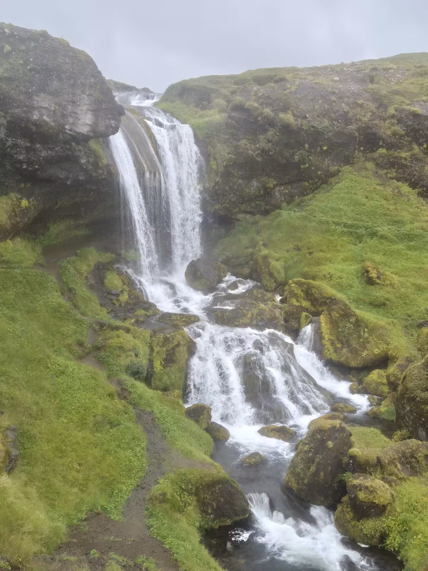 Cascading waterfall over mossy green rocks on the Snaefellsnes Peninsula, Iceland