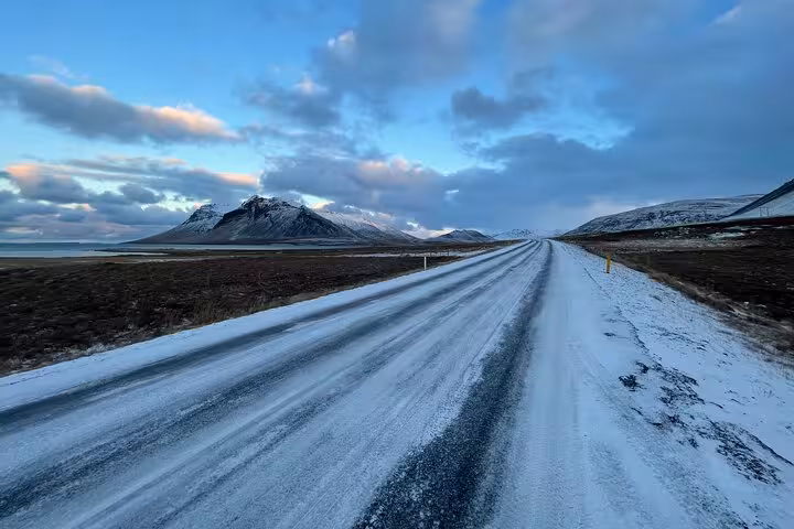 Snow-covered road leading toward volcanic mountains on Snaefellsnes Peninsula in winter