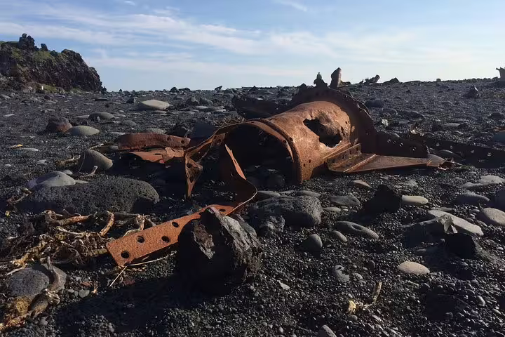Rusty shipwreck debris scattered on black volcanic pebble beach in Snaefellsnes Peninsula, Iceland