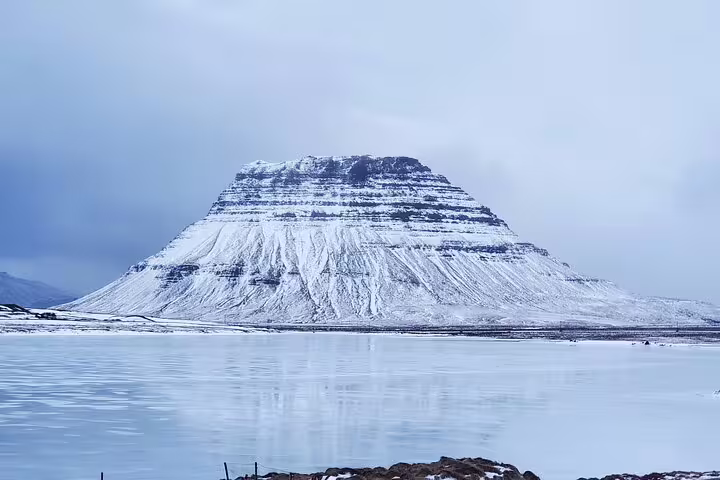 Snow-covered flat-topped mountain reflecting on a calm icy lake during a Snaefellsnes Peninsula private day trip from Reykjavik.