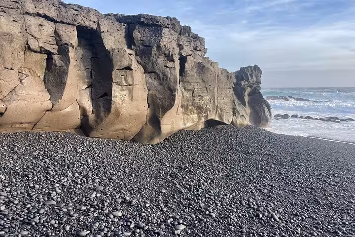 Black pebble beach with dramatic volcanic cliffs and ocean waves at Snaefellsnes Peninsula, Iceland