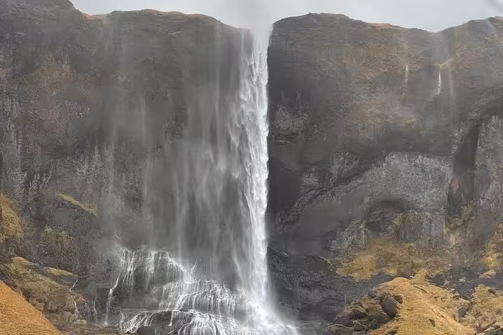 Powerful waterfall cascading down dark volcanic cliffs on Snaefellsnes Peninsula, Iceland