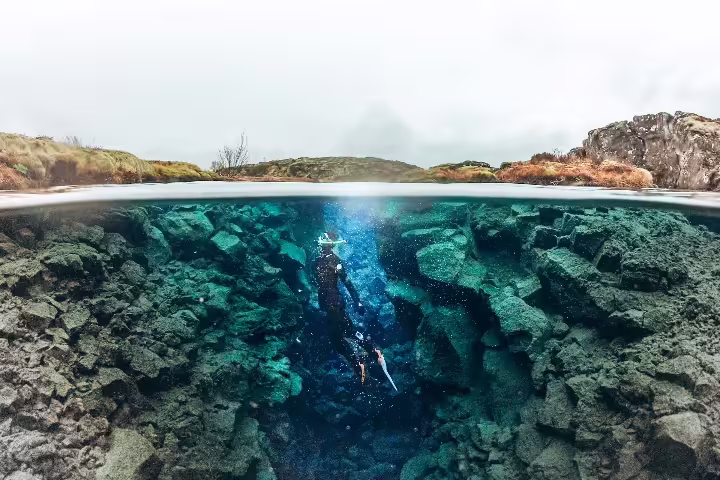 Snorkeler explores the clear, vibrant waters between tectonic plates in Silfra, Iceland, showcasing unique underwater scenery.