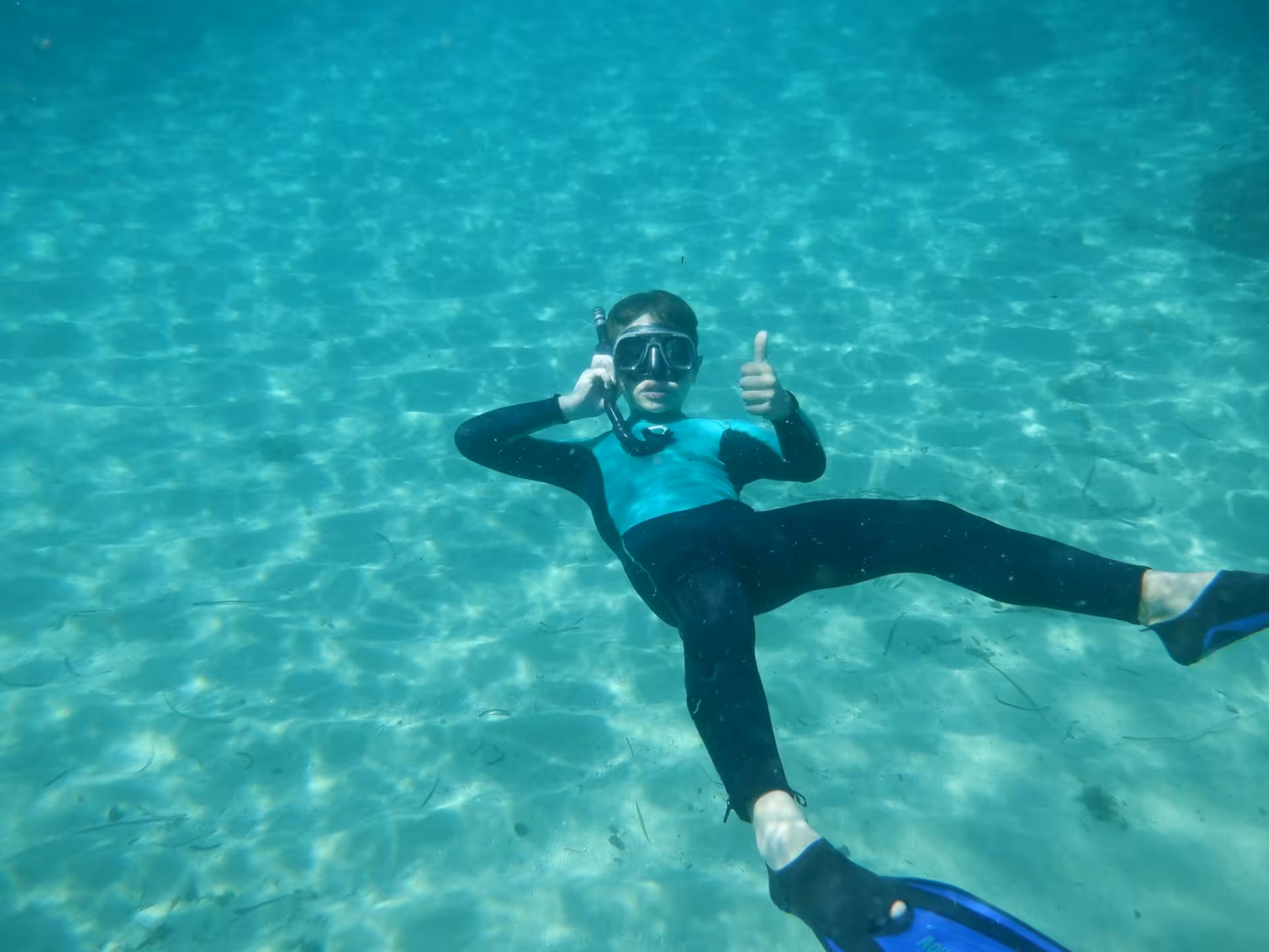 Underwater view of a snorkeler giving thumbs up, enjoying clear waters in Bay of Balai, Porto Torres.
