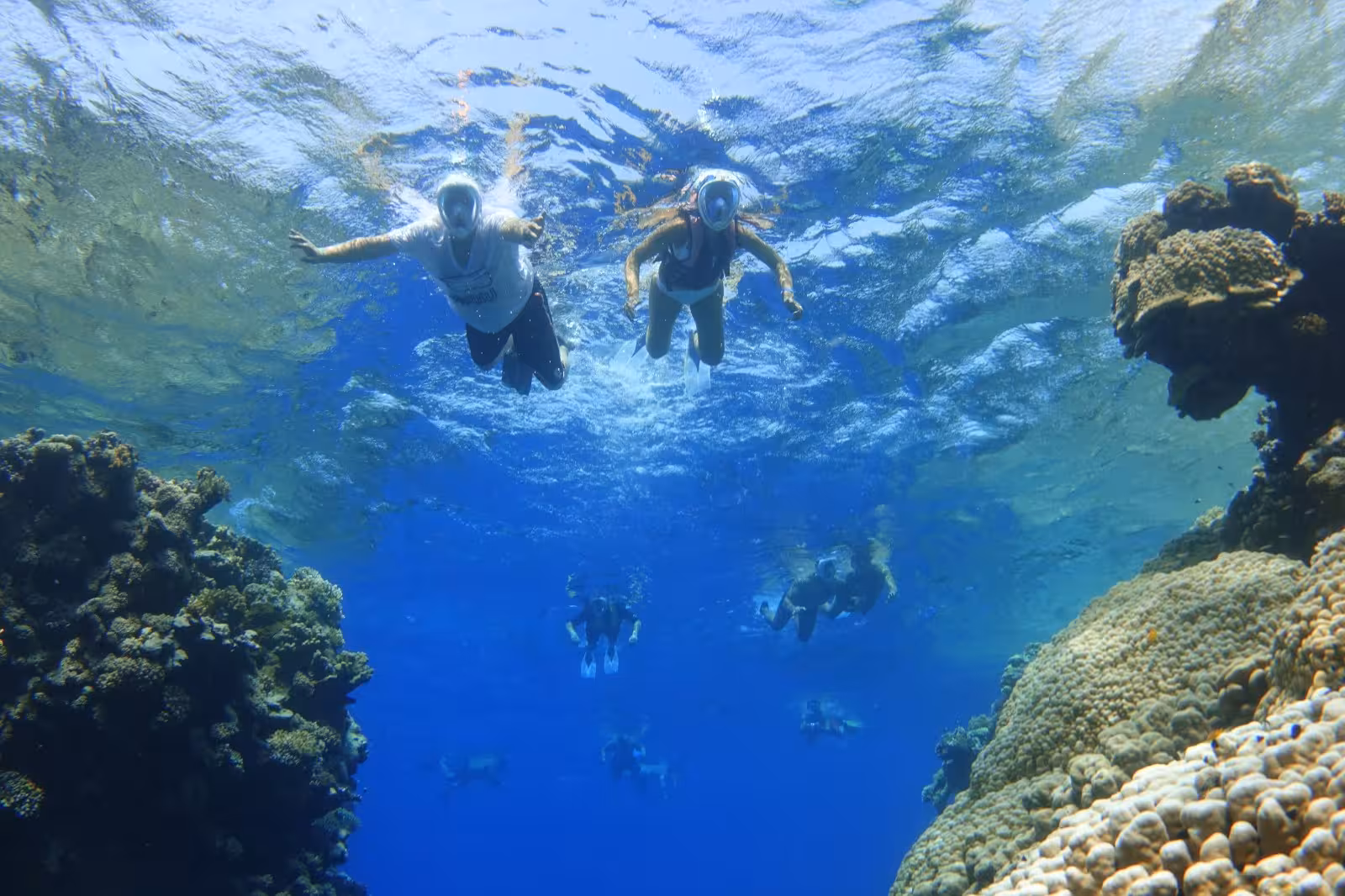 Snorkelers swimming above vibrant coral reef at Sataya Reef with crystal blue water