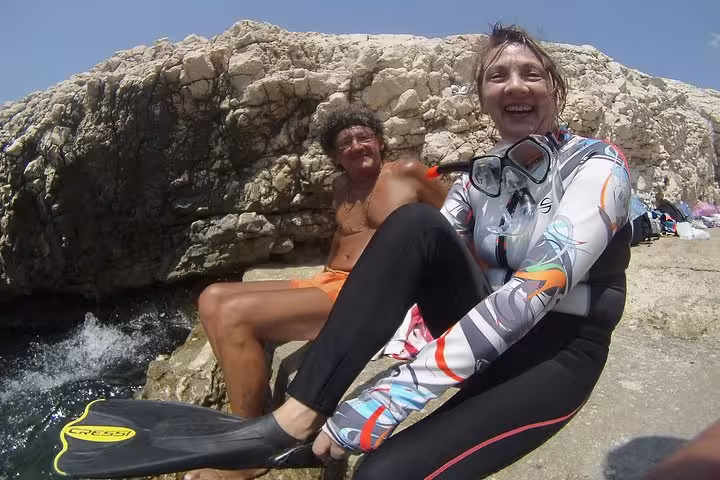 Snorkelers resting on seaside rocks during Rando-Palmée Getaway around an island, guided coastal break