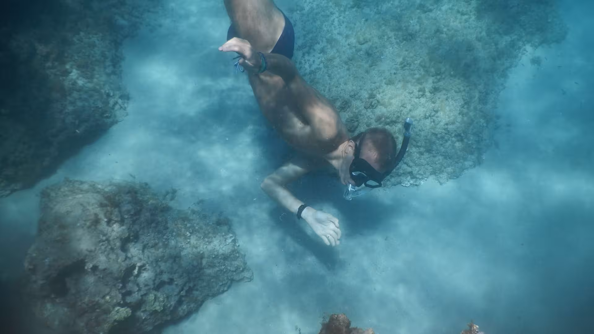 Man exploring vibrant coral reefs while snorkeling in the pristine waters of Orosei Gulf, Cala Gonone.