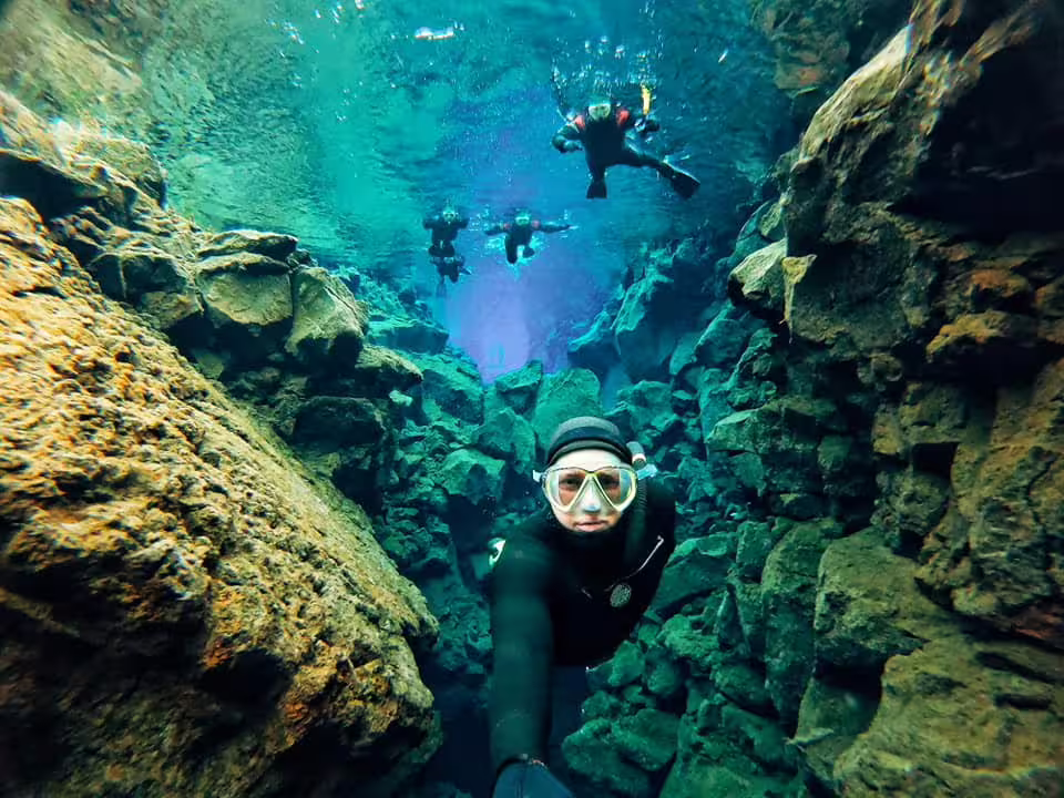 Snorkelers explore the crystal-clear waters between tectonic plates in Silfra, Iceland, showcasing vibrant underwater scenery.