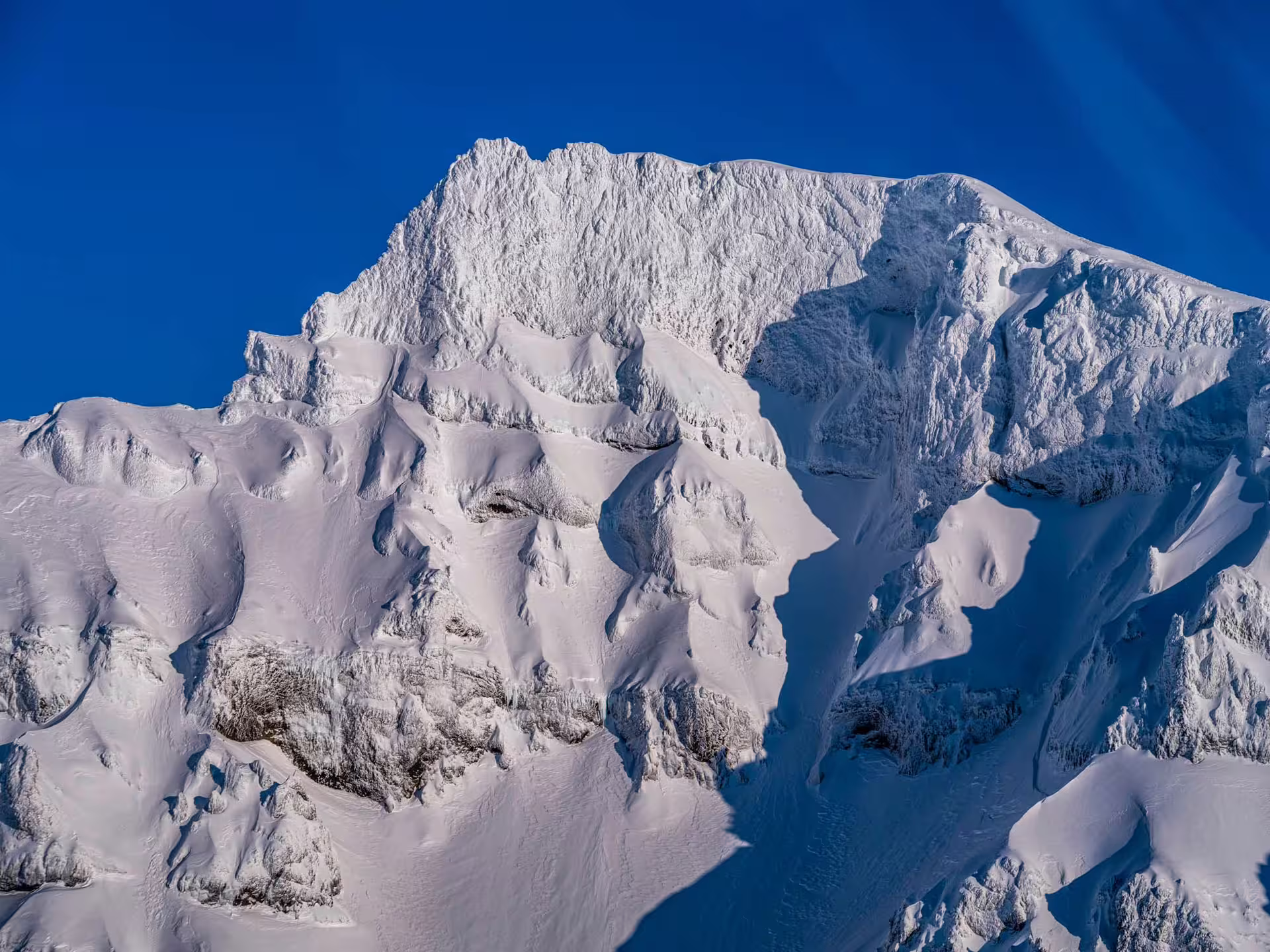 Snow-covered volcanic mountain peaks under a clear blue sky near Skaftafell Iceland