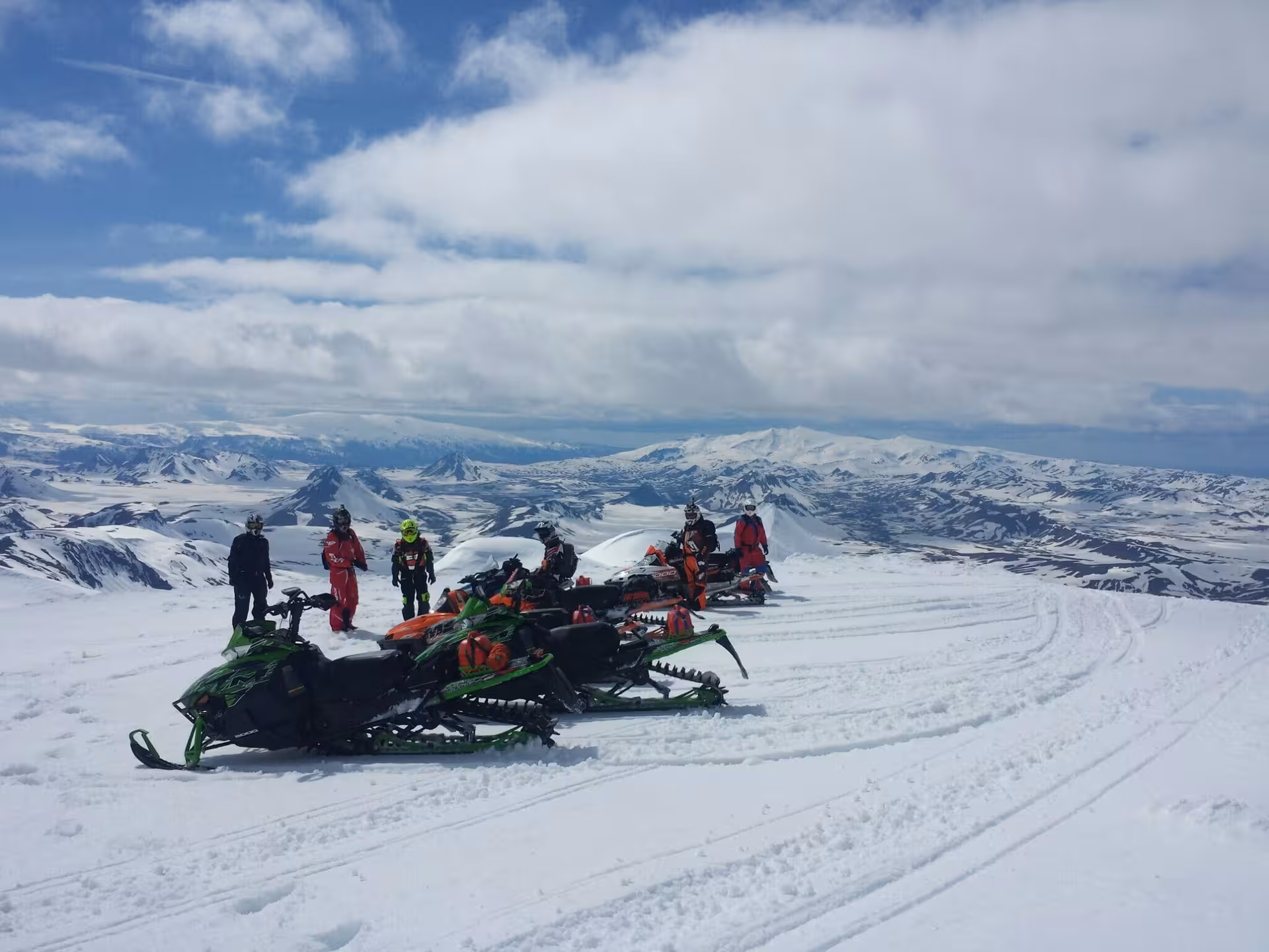 Group of snowmobilers on Arctic Cat sleds resting on snowy Landmannalaugar highlands with mountain panorama