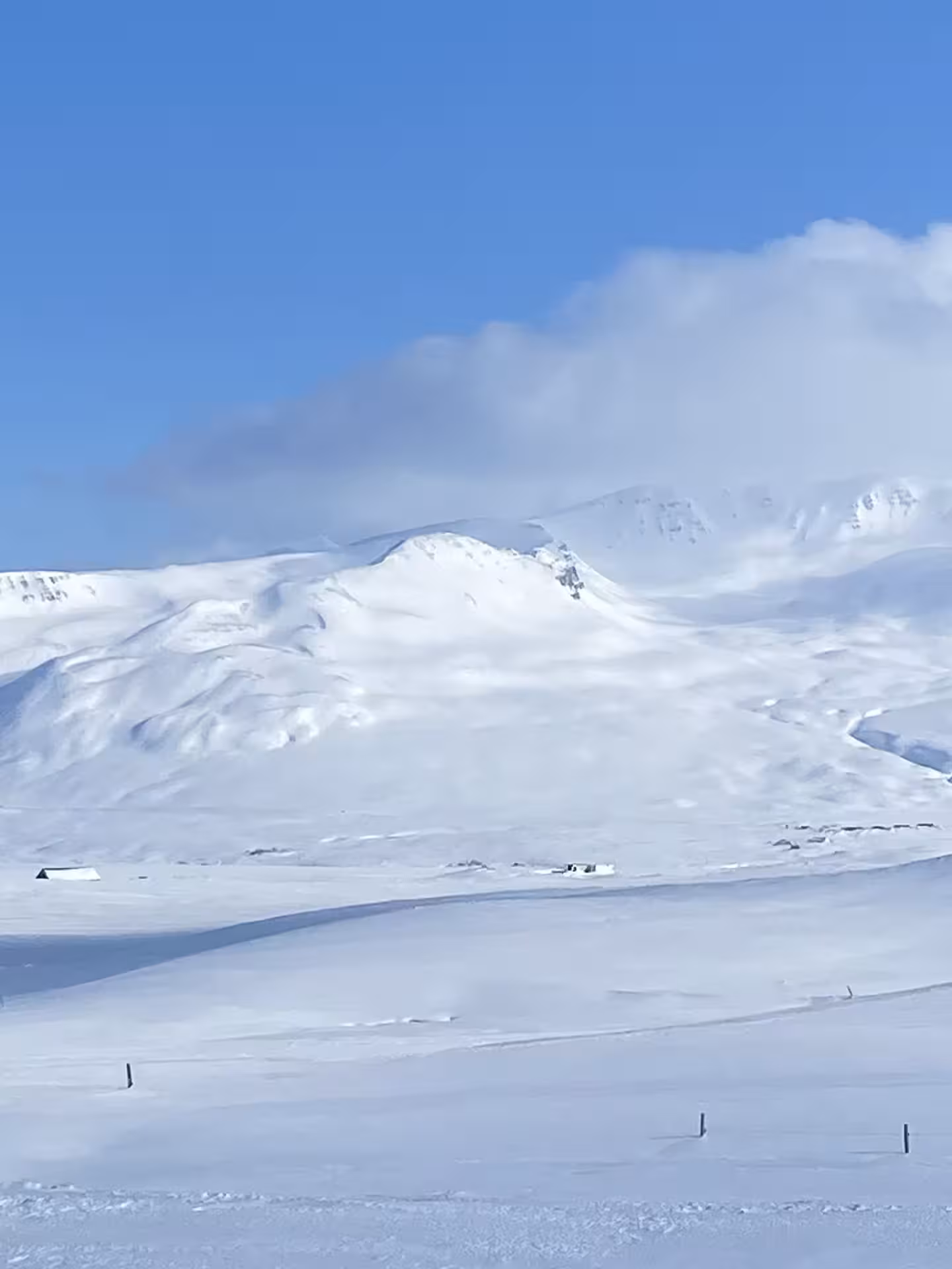 Snow-covered mountain terrain under a clear blue sky during a snowshoe and float half-day tour in North Iceland.