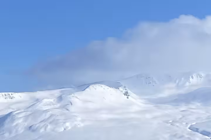Panoramic snowy mountains in Fljótin, Iceland, on a winter snowshoeing and flotation tour with clear blue sky