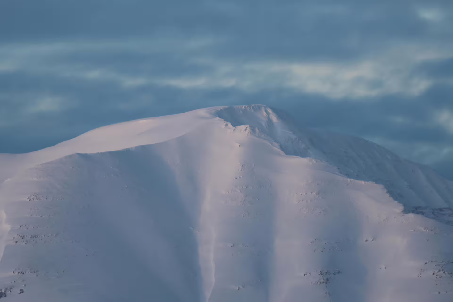 Snow-covered mountain peak near Akureyri Iceland under blue winter sky