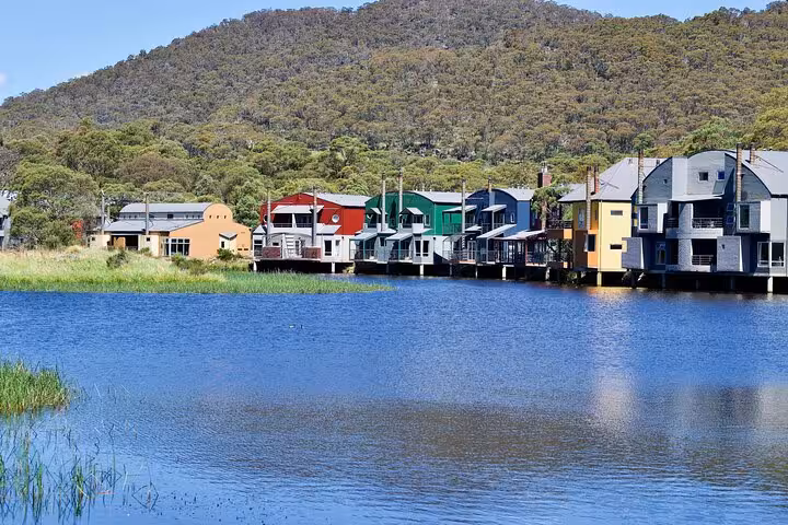Colorful lakeside cabins nestled in lush greenery, perfect for scenic views on the Snowy Mountains NSW private tour.