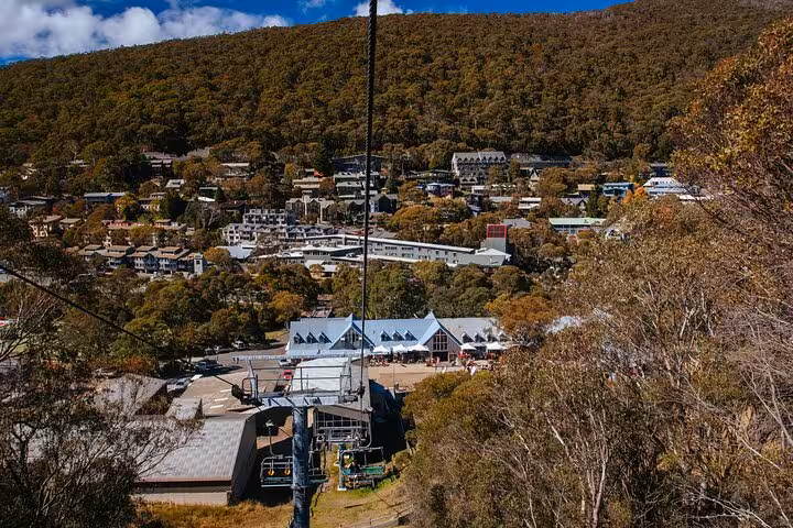 Aerial view of a quaint mountain village with lush forest backdrop, featured in the Snowy Mountains NSW private tour.