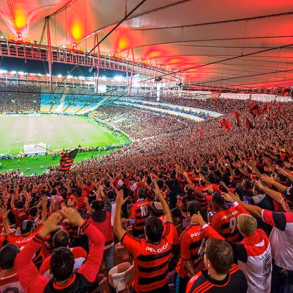 Packed stadium with enthusiastic fans waving flags during a soccer match at Maracanã Stadium, Rio de Janeiro.