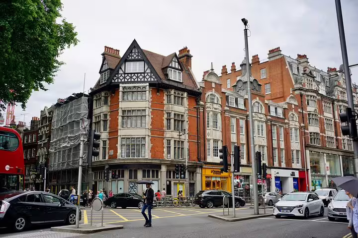 Victorian brick buildings at a busy London street corner in Soho with pedestrians and traffic