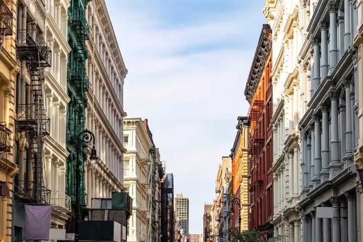 Historic cast-iron buildings lining a narrow SoHo NYC street with fire escapes and ornate facades