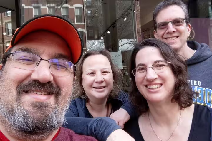 Four smiling adults posing for a selfie on a SoHo NYC street
