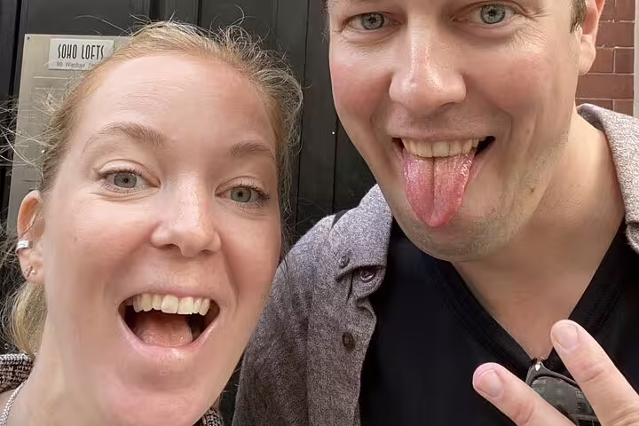 Two smiling visitors posing outside Soho Lofts on a rock and roll walking tour