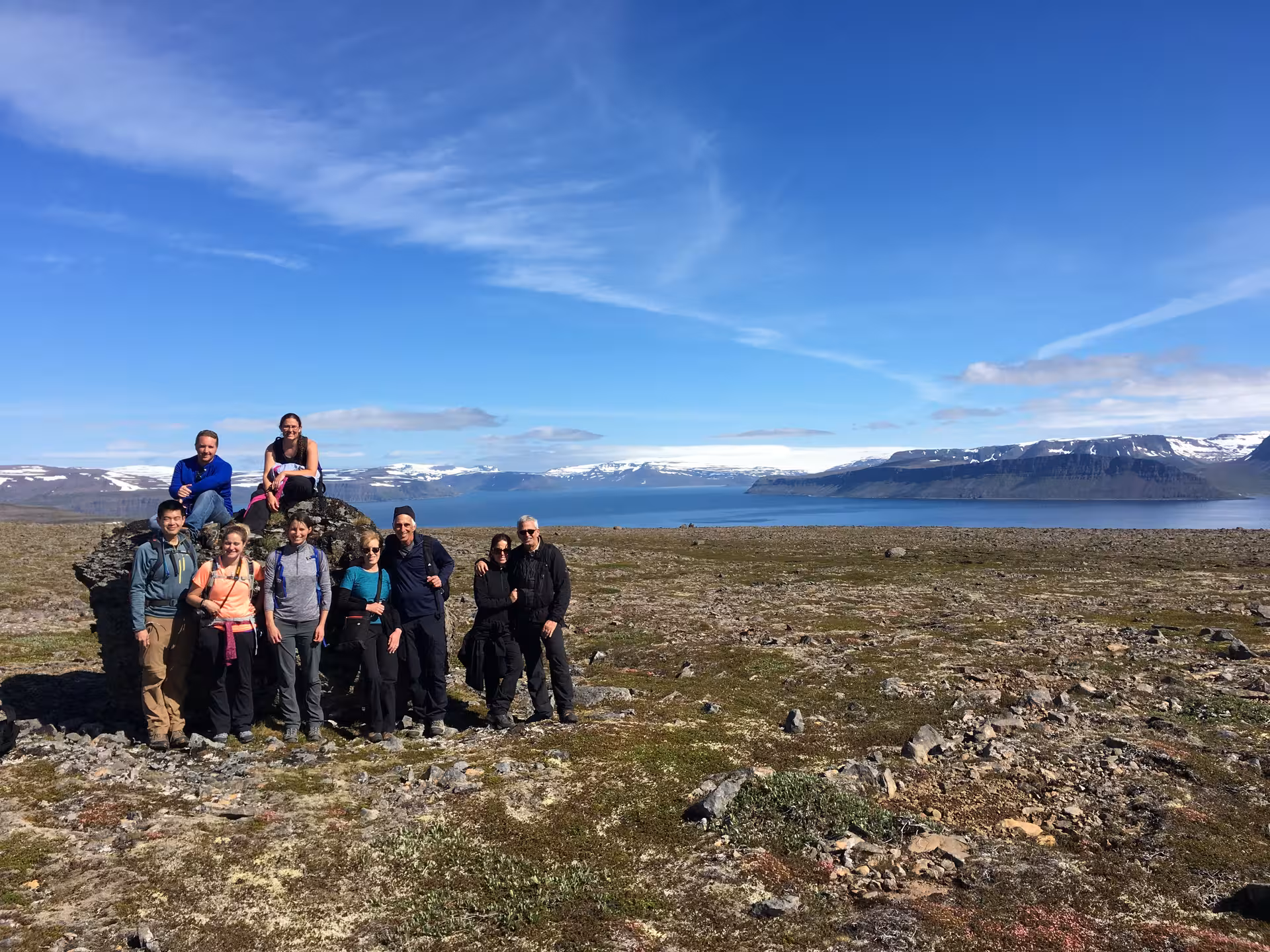 Group photo on rocky tundra overlooking fjord and snowcapped peaks, Solar Eclipse Hike tour experience