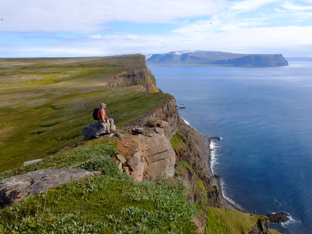 Hiker on dramatic sea cliffs during Solar Eclipse Hike tour, panoramic coastal views and rugged trail
