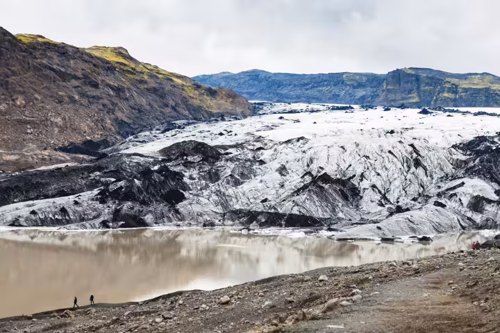 Panoramic view of Solheimajokull Glacier with ash-streaked ice and glacial lagoon on a guided South Iceland hike tour