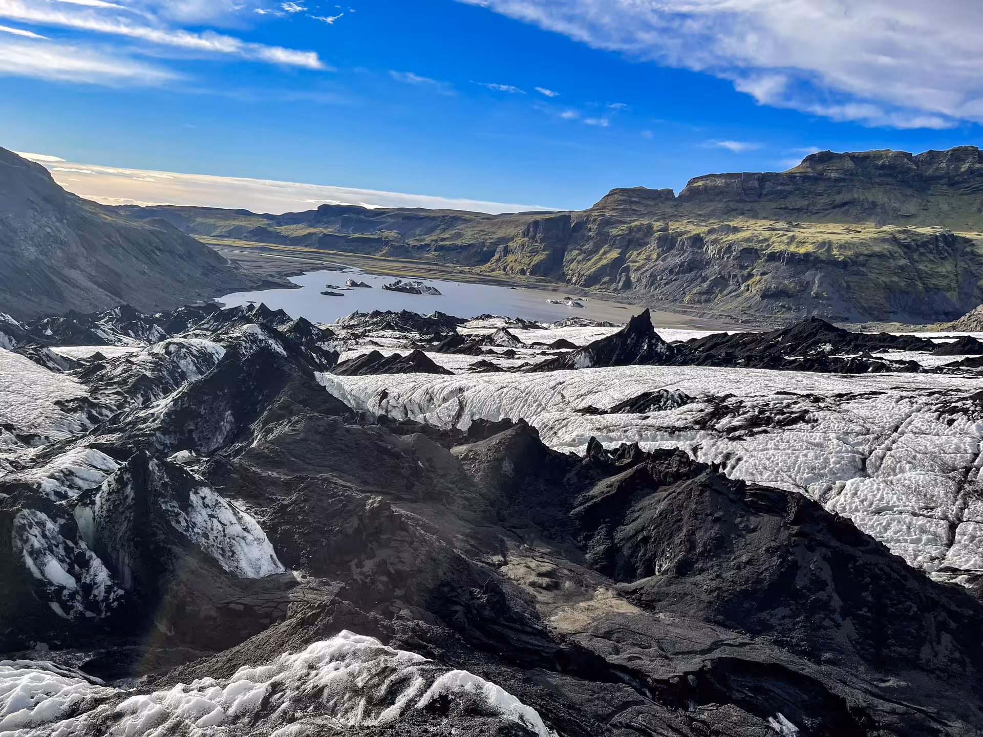 Aerial view of Sólheimajökull glacier with black volcanic ash, ice formations, and glacial lagoon in Iceland