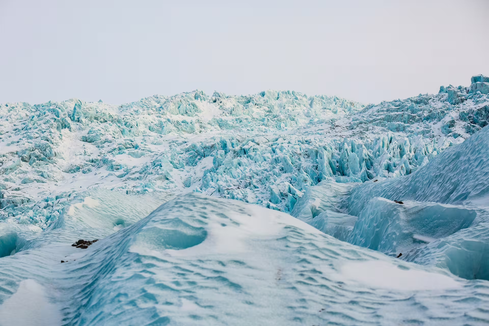 Jagged blue ice formations and snow-covered terrain on Solheimajokull glacier in Iceland