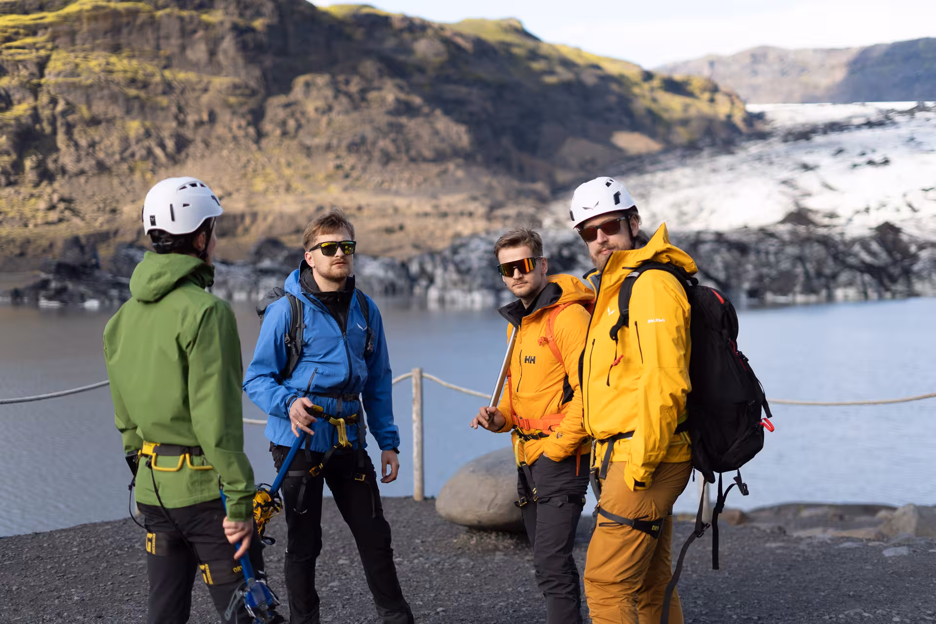 Guides brief hikers with helmets and ice axes by Sólheimajökull glacier lagoon before the glacier hike