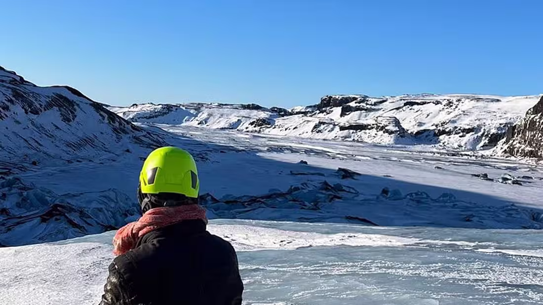 A lone person standing on top of a glacier with their back to the camera