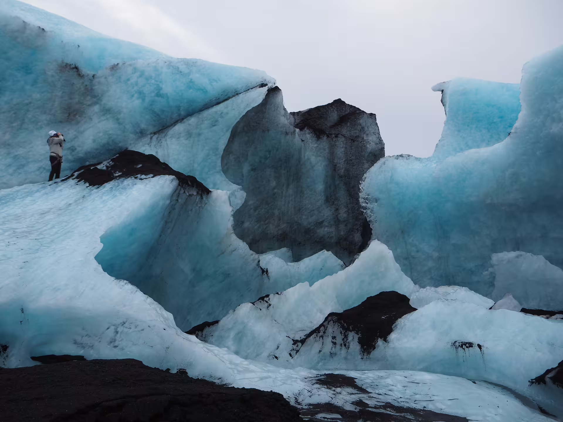 Hiker standing on blue ice formations at Solheimajokull glacier in southern Iceland
