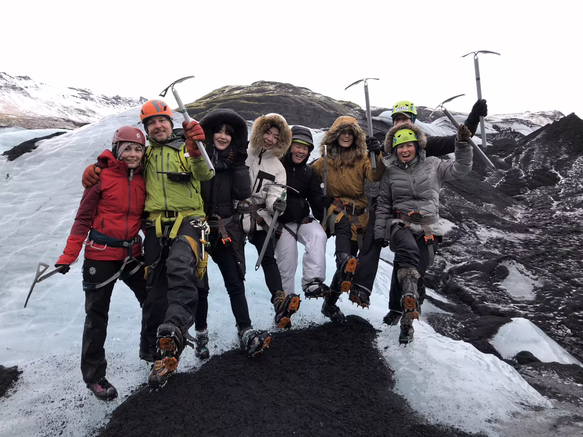 Group of hikers with ice axes and crampons posing on Solheimajokull glacier in Iceland