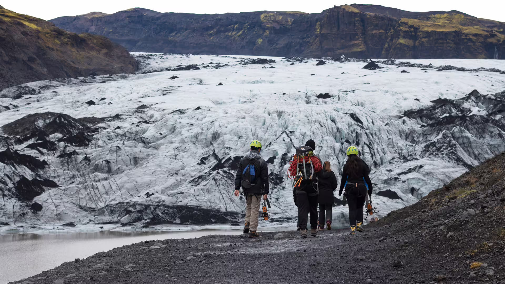 Group of hikers with crampons and helmets approaching Solheimajokull glacier in Southern Iceland