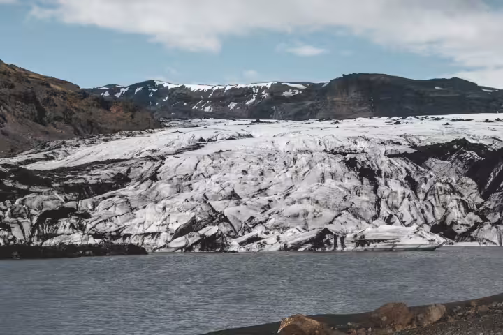 Stunning view of Solheimajokull Glacier with glacial lagoon and volcanic black sand on a private Iceland hike tour